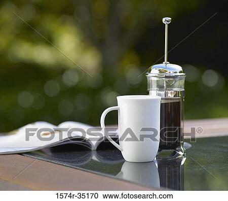 Coffee cup and a plunger with a magazine on a table View Large Photo Image Stock Image - Coffee cup and a plunger with a magazine on a table. Fotosearch