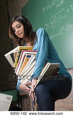 Female university student carrying a stack of books View Large Photo Image Stock Image - Female university student carrying a stack of books. Fotosearch