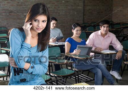 Female university student talking on a mobile phone in a classroom View Large Photo Image Stock Image - Female university student talking on a mobile phone in a classroom. Fotosearch