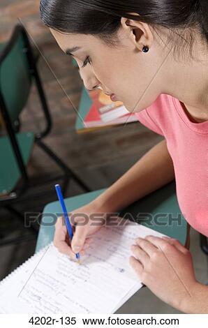 Female university student writing in a classroom View Large Photo Image Stock Photography - Female university student writing in a classroom. Fotosearch