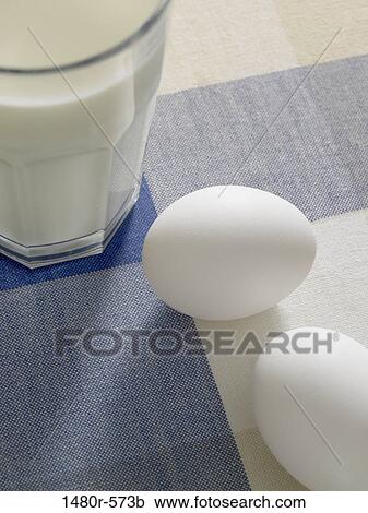 Stock Image - Glass of milk with eggs on a table. Fotosearch