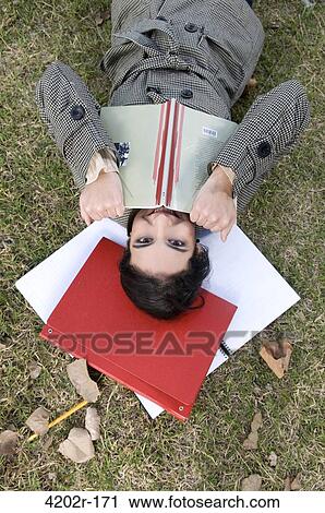 High angle view of a female university student lying on grass and smiling View Large Photo Image Stock Image - High angle view of a female university student lying on grass and smiling. Fotosearch
