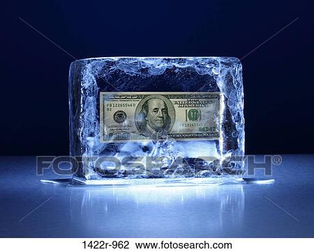 Stock Image - Large block of ice with one hundred dollar bill frozen inside. Fotosearch