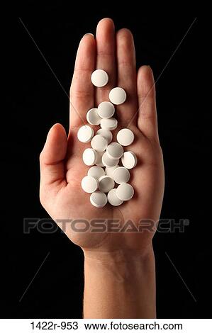 Stock Image - Many white pills in the palm of a person. Fotosearch