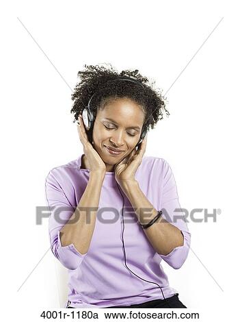 Mid adult woman listening to music with headphones View Large Photo Image Stock Image - Mid adult woman listening to music with headphones. Fotosearch