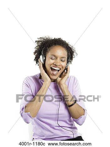 Stock Image - Mid adult woman listening to music with headphones. Fotosearch