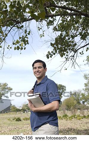 Portrait of a male university student holding books View Large Photo Image Stock Photograph - Portrait of a male university student holding books. Fotosearch