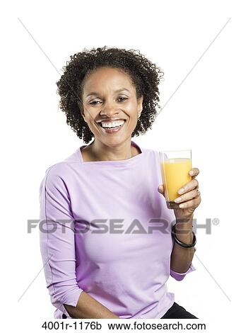 Stock Image - Portrait of a mid adult woman holding a glass of orange juice. Fotosearch