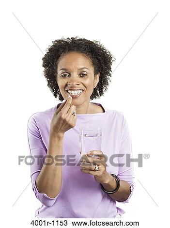 Stock Image - Portrait of a mid adult woman taking medicine. Fotosearch