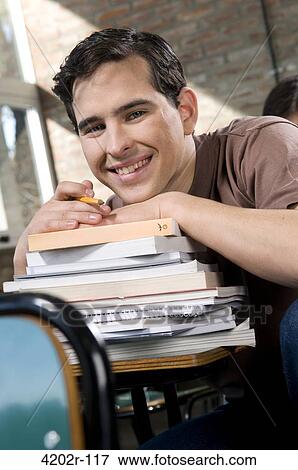 Stock Photo - Portrait of a young man sitting at a desk in a classroom. Fotosearch