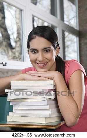 Portrait of a young woman in a classroom with pile of books View Large Photo Image Stock Photograph - Portrait of a young woman in a classroom with pile of books. Fotosearch