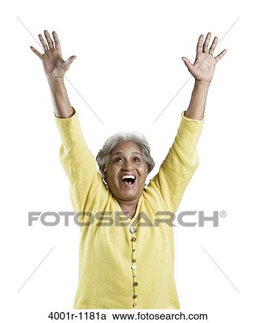 Senior woman standing with her arms raised and looking excited View Large Photo Image Stock Image - Senior woman standing with her arms raised and looking excited. Fotosearch