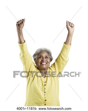 Senior woman standing with her arms raised and looking excited View Large Photo Image Stock Image - Senior woman standing with her arms raised and looking excited. Fotosearch