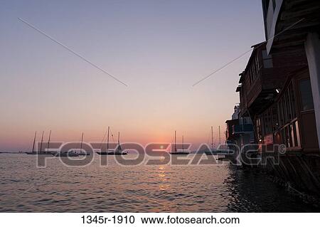 Stock Image - Silhouette of boats at sunset, Mykonos Town, Mykonos, Cyclades Islands, Greece. Fotosearch