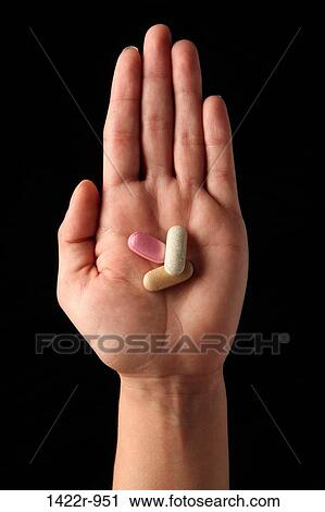 Stock Image - Three colorful capsules in the palm of a person. Fotosearch