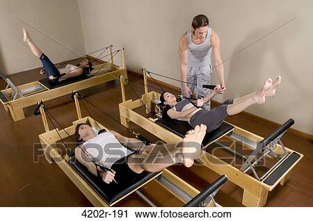Trainer assisting people in a gym View Large Photo Image Stock Image - Trainer assisting people in a gym. Fotosearch