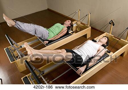 Two young men exercising in a gym View Large Photo Image Stock Photograph - Two young men exercising in a gym. Fotosearch
