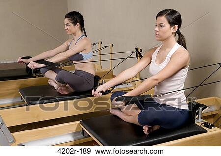 Two young women working out with Pilates exercise machine in a gym View Large Photo Image Stock Photo - Two young women working out with Pilates exercise machine in a gym. Fotosearch