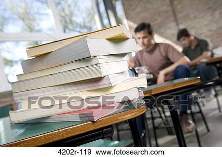 University students in a classroom with a stack of books View Large Photo Image Stock Photo - University students in a classroom with a stack of books. Fotosearch