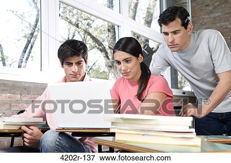 University students working on a laptop in a classroom View Large Photo Image Stock Photo - University students working on a laptop in a classroom. Fotosearch