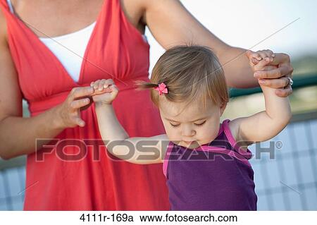 Woman helping her daughter to walk View Large Photo Image Stock Image - Woman helping her daughter to walk. Fotosearch