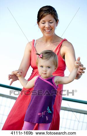 Woman helping her daughter to walk View Large Photo Image Stock Image - Woman helping her daughter to walk. Fotosearch