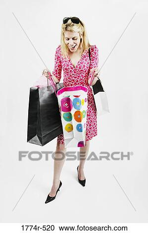 Woman looking into her shopping bags and smiling View Large Photo Image Stock Image - Woman looking into her shopping bags and smiling. Fotosearch