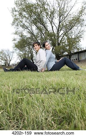 Stock Photo - Young couple sitting in the grass in campus. Fotosearch