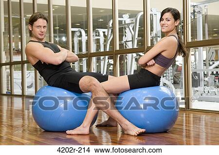 Young couple sitting on fitness balls in a gym View Large Photo Image Picture - Young couple sitting on fitness balls in a gym. Fotosearch