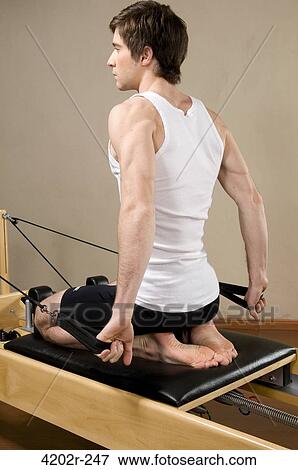 Young man exercising in a gym View Large Photo Image Stock Photo - Young man exercising in a gym. Fotosearch