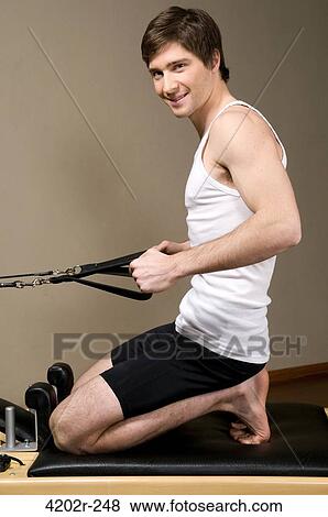Young man exercising in a gym View Large Photo Image Stock Photo - Young man exercising in a gym. Fotosearch