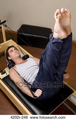 Young man exercising in a gym View Large Photo Image Stock Photograph - Young man exercising in a gym. Fotosearch