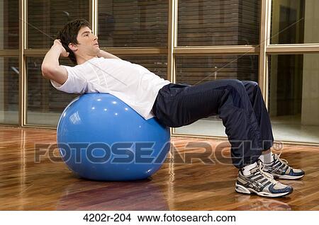 Young man exercising on a fitness ball View Large Photo Image Picture - Young man exercising on a fitness ball. Fotosearch