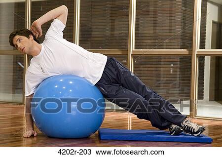 Young man exercising on a fitness ball View Large Photo Image Stock Image - Young man exercising on a fitness ball. Fotosearch