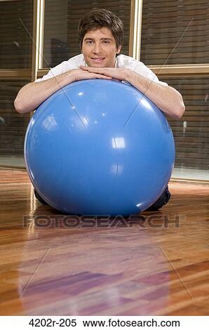 Young man leaning over a fitness ball View Large Photo Image Stock Photography - Young man leaning over a fitness ball. Fotosearch