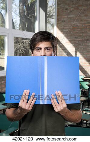 Young man peeking over opened book View Large Photo Image Stock Image - Young man peeking over opened book. Fotosearch