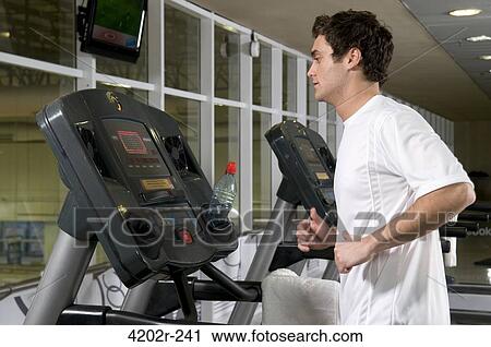 Young man running on a treadmill View Large Photo Image Stock Image - Young man running on a treadmill. Fotosearch