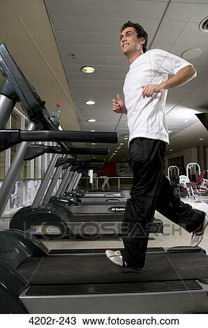 Young man running on a treadmill View Large Photo Image Stock Image - Young man running on a treadmill. Fotosearch