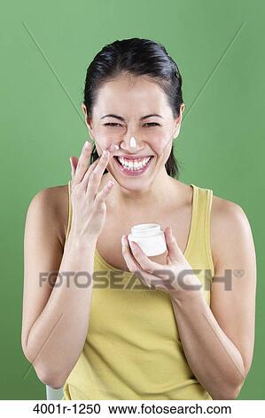 Young woman applying moisturizer on her face View Large Photo Image Stock Image - Young woman applying moisturizer on her face. Fotosearch