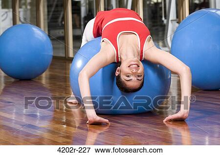 Stock Photo - Young woman exercising on a fitness ball. Fotosearch