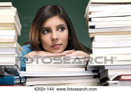 Young woman resting head on books in a classroom View Large Photo Image Picture - Young woman resting head on books in a classroom. Fotosearch