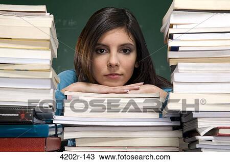 Young woman resting head on books in a classroom View Large Photo Image Stock Image - Young woman resting head on books in a classroom. Fotosearch