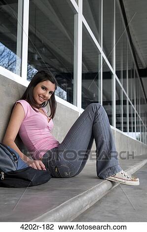 Young woman sitting outside a university and smiling View Large Photo Image Stock Image - Young woman sitting outside a university and smiling. Fotosearch