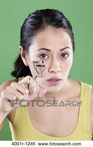 Young woman using an eyelash curler View Large Photo Image Stock Photography - Young woman using an eyelash curler. Fotosearch