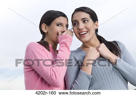 Young woman whispering to her friend View Large Photo Image Stock Image - Young woman whispering to her friend. Fotosearch