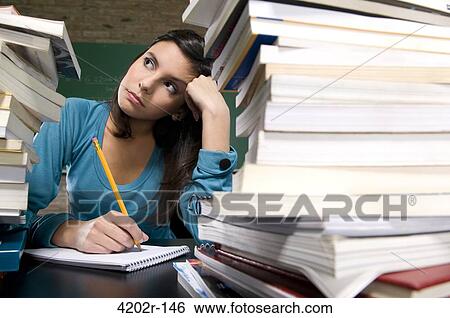 Young woman writing in a textbook and thinking View Large Photo Image Stock Photograph - Young woman writing in a textbook and thinking. Fotosearch
