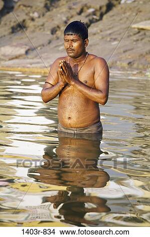 A man stands praying in the Ganges River at the holy Hindu city of Varanasi, India in Uttar Pradesh state View Large Photo Image Picture - A man stands praying in the Ganges River at the holy Hindu city of Varanasi, India in Uttar Pradesh state. Fotosearch