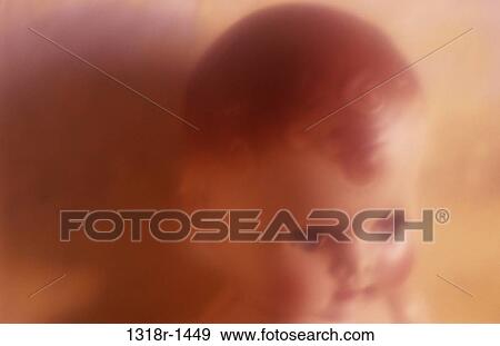Stock Photo - Atmospheric close up from above of face and head of traditional baby doll with staring blue eyes casting shadow in warm light Norfolk UK. Fotosearch