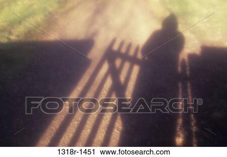 Atmospheric shadows of hooded figure standing at or passing thru wooden wicket gate in wall Norfolk UK View Large Photo Image Stock Image - Atmospheric shadows of hooded figure standing at or passing thru wooden wicket gate in wall Norfolk UK. Fotosearch