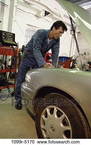 Auto mechanic working over the engine bay of a car View Large Photo Image Stock Image - Auto mechanic working over the engine bay of a car. Fotosearch